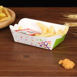A food tray in green and white, featuring colourful dots and a floral design, filled with fries and a sauce packet.