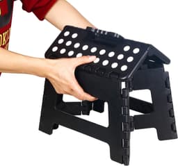 A black 11-inch folding step stool with a handle and holes for grip, being held by a hand.