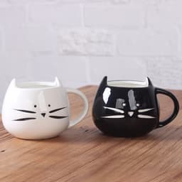 A cute set of two ceramic cat coffee mugs, one black and one white, featuring playful cat face designs.