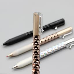 A Crinkle Grip Pen with a textured rose gold grip, alongside black, white, and silver pens, all featuring a clip.