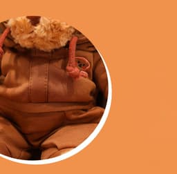 A brown plush teddy bear wearing a matching brown outfit, featuring a small logo on the clothing.