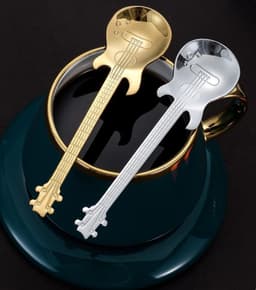 A gold and silver guitar-shaped spoon resting on a dark green plate beside a black cup.