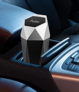 A geometric black and white car trash can sits in a car's cup holder, featuring a 'PUSH' top and a sleek design.