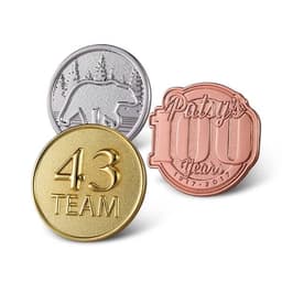 Three sandblasted die struck pins in gold, silver, and copper colours, featuring different designs and a logo.