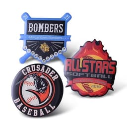 Three vibrant trading pins: a blue baseball-themed design, a black and orange Crusader Baseball pin, and a red Allstars Softball pin.