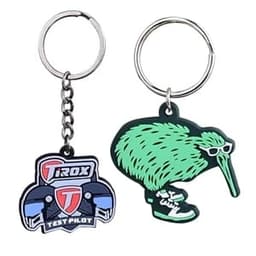 Two custom 2D PVC keychains: one features a logo and the other is a green kiwi wearing sunglasses and sneakers.