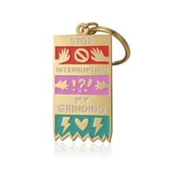 A gold keychain featuring multicoloured soft enamel sections with various symbols and a logo.