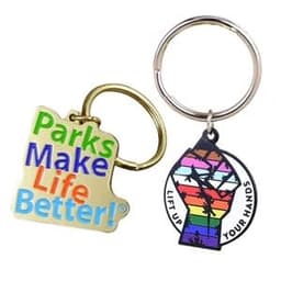 Two hard enamel keychains featuring a colourful design with the phrase "Parks Make Life Better!" and a rainbow fist logo.