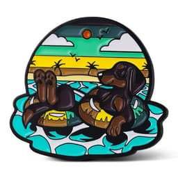 A colourful lapel pin featuring a dog lounging on a float in a tropical setting with waves and sun.