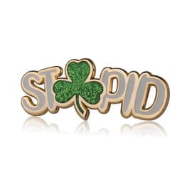 A gold and green lapel pin featuring the word "STP" alongside a green glittery clover.