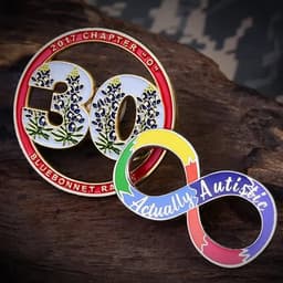 A set of two lapel pins featuring a circular design with flowers and an infinity symbol in rainbow colours with text.