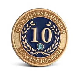 A gold and navy lapel pin featuring the number 10 and a decorative wreath design, with a small blue gemstone.