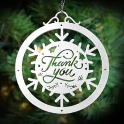 A silver cut-out ornament featuring a snowflake design and the words "Thank You", hanging on a tree backdrop.