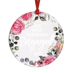A round acrylic ornament featuring pink roses and greenery, with text celebrating an engagement and the year 2023.