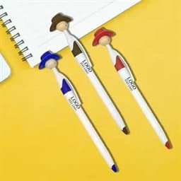 A set of three pens with cowboy figure tops in blue, red, and brown, resting on a yellow background with a notepad.