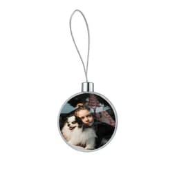 A round silver pendant featuring a photo of a girl with a small dog inside. It has a hanging loop attached.