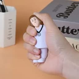 A white doctor stress ball featuring a cartoon figure with brown hair, held in a hand against a neutral background.