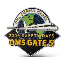 A custom enamel pin featuring a stylised airplane, globe design, and bold text in yellow and blue colours.