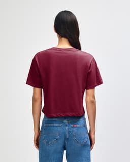 A maroon women's fine jersey boxy T-shirt, viewed from the back, paired with light blue baggy jeans.