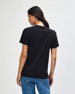 A black heavyweight cotton unisex T-shirt displayed on a model from the back, featuring a simple design and loose fit.