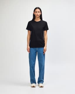 A black heavyweight cotton unisex T-shirt displayed on a model, paired with green cargo pants and sneakers.