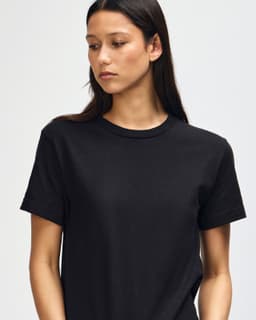 A unisex heavyweight cotton T-shirt in black, featuring a logo, worn by a model with a shaved head.