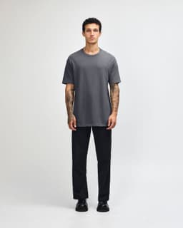 A unisex heavyweight cotton t-shirt in grey, paired with light blue jeans and black sneakers, featuring a logo.