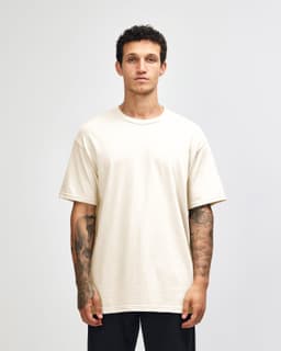 A heavyweight cotton unisex T-shirt in a light cream colour, featuring a standard crew neck and short sleeves.