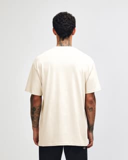 A cream heavyweight cotton unisex T-shirt displayed on a model, featuring short sleeves and a plain back.
