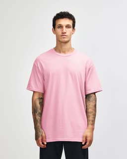 A unisex heavyweight cotton T-shirt in pink, worn by a model, with a simple and casual design.