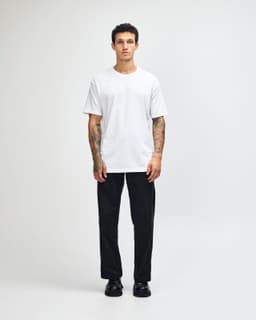 A lightweight white unisex T-shirt displayed on a model wearing baggy blue jeans and black sneakers, featuring a logo.