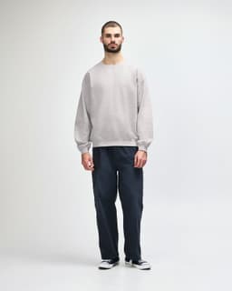 A grey Gildan Heavy Blend adult crewneck sweatshirt worn by a model, paired with black jeans and sneakers.