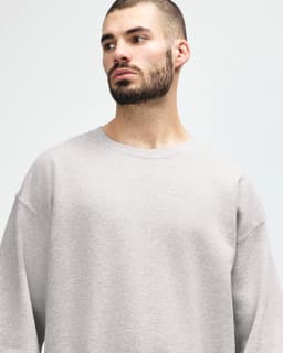 A grey Gildan Heavy Blend adult crewneck sweatshirt with long sleeves, featuring a logo.