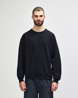 A black Gildan Heavy Blend adult crewneck sweatshirt displayed on a model wearing blue jeans.