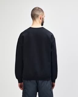 A black Gildan Heavy Blend adult crewneck sweatshirt, viewed from the back, paired with blue jeans.
