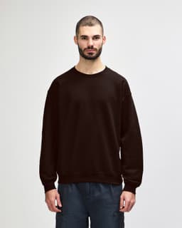 A brown Gildan Heavy Blend adult crewneck sweatshirt with long sleeves, worn by a model.