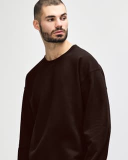 A brown Gildan Heavy Blend adult crewneck sweatshirt displayed on a model, featuring a simple design and a logo.