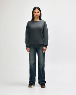 A grey Gildan Heavy Blend adult crewneck sweatshirt worn by a model, paired with black jeans and sneakers.