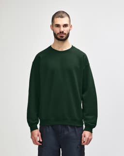 A green Gildan Heavy Blend adult crewneck sweatshirt on a model, featuring a plain design and long sleeves.