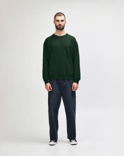 A green Gildan Heavy Blend adult crewneck sweatshirt worn by a model, paired with black jeans and sneakers.