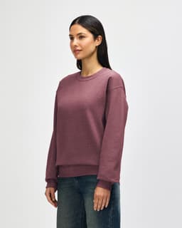 A crewneck sweatshirt in a dusty rose colour, featuring long sleeves and a relaxed fit. It has a branding logo.