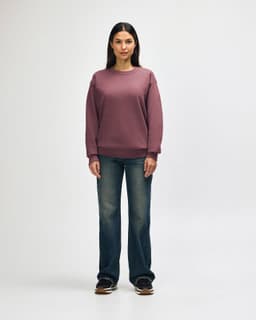 A man wearing a maroon Gildan Heavy Blend crewneck sweatshirt paired with black jeans and sneakers.