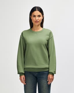 A green crewneck sweatshirt worn by a person, featuring a relaxed fit and long sleeves. It has a logo on the sleeve.