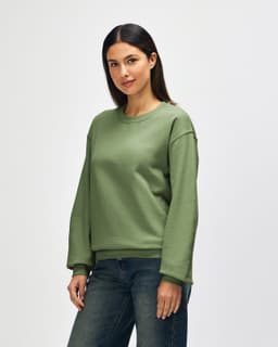 A man wearing a green crewneck sweatshirt, featuring long sleeves and a relaxed fit. The sweatshirt has a logo.