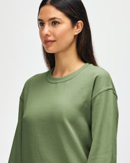 An olive green Gildan Heavy Blend adult crewneck sweatshirt with a model showcasing its fit and design.