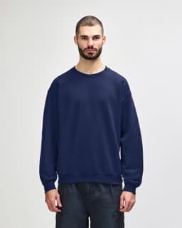A navy blue crewneck sweatshirt with a relaxed fit, featuring long sleeves and ribbed cuffs. It has a logo.