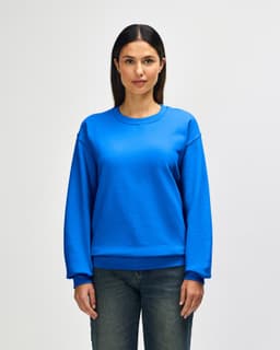 A blue Gildan Heavy Blend adult crewneck sweatshirt on a model, featuring long sleeves and a relaxed fit.