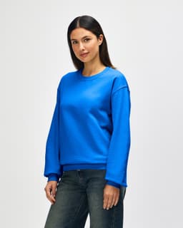 A blue Gildan Heavy Blend adult crewneck sweatshirt displayed on a model, featuring a casual fit and long sleeves.