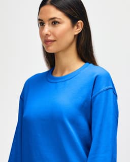 A blue Gildan Heavy Blend adult crewneck sweatshirt on a model with a neutral background, featuring a logo.