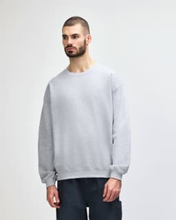 A grey Gildan Heavy Blend Adult Crewneck Sweatshirt displayed on a model, featuring a classic crew neckline and long sleeves.